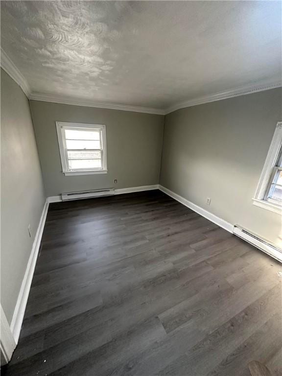 spare room featuring dark hardwood / wood-style flooring, baseboard heating, and crown molding