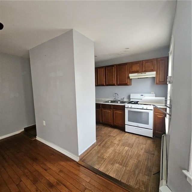 kitchen with wood-type flooring, white range, a baseboard radiator, and sink