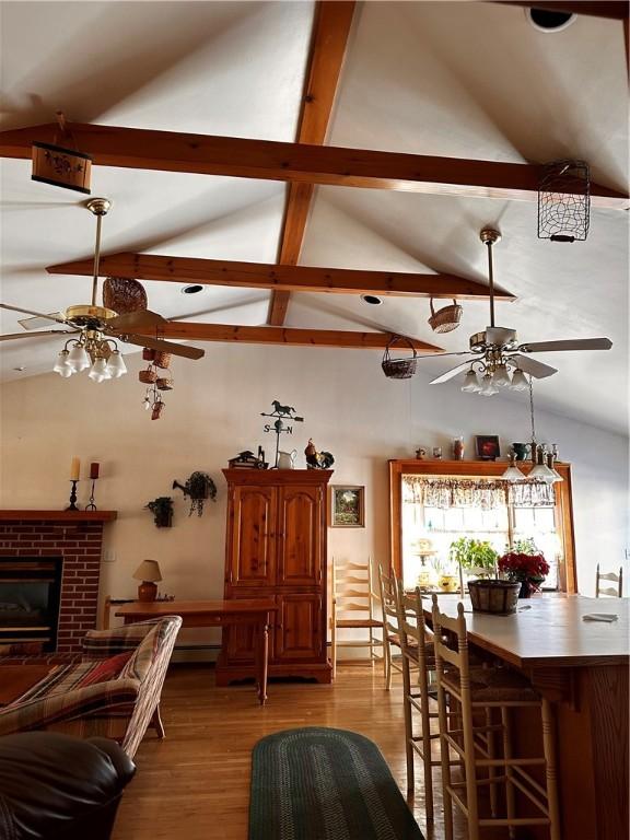 interior space featuring light wood-type flooring, lofted ceiling with beams, and a fireplace