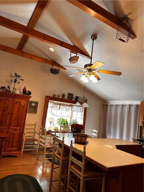 dining space with light wood-type flooring, ceiling fan, and lofted ceiling with beams