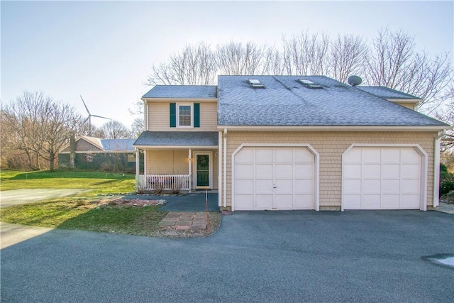 view of property featuring a garage, a front yard, and covered porch