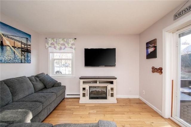 living room featuring light hardwood / wood-style floors, a baseboard radiator, and a fireplace