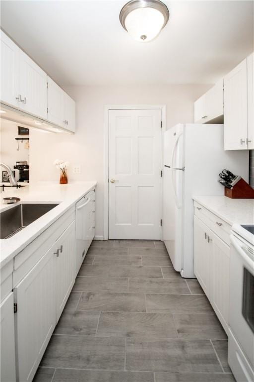 kitchen featuring white appliances, white cabinetry, and sink