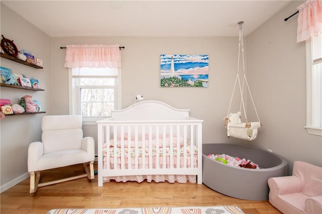 bedroom with wood-type flooring and a crib