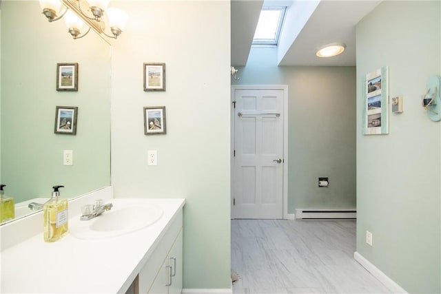 bathroom with a baseboard radiator, vanity, a skylight, and a notable chandelier