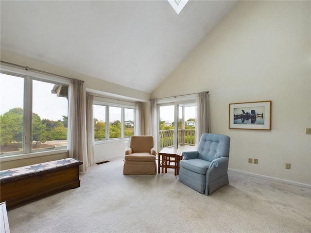 living area with light carpet, a skylight, and high vaulted ceiling