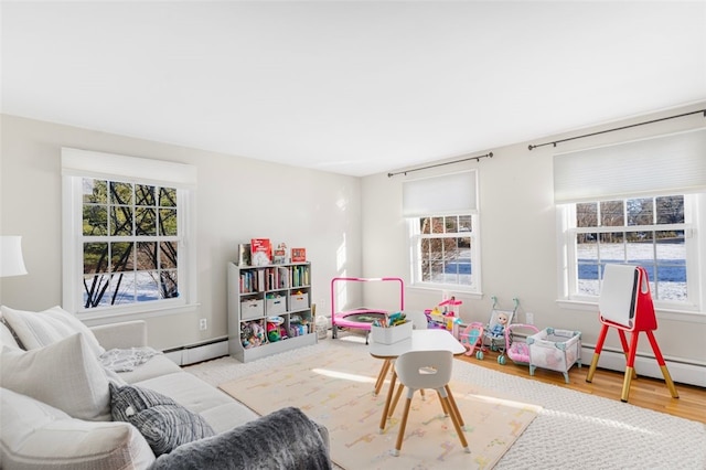 rec room with baseboard heating and light hardwood / wood-style floors