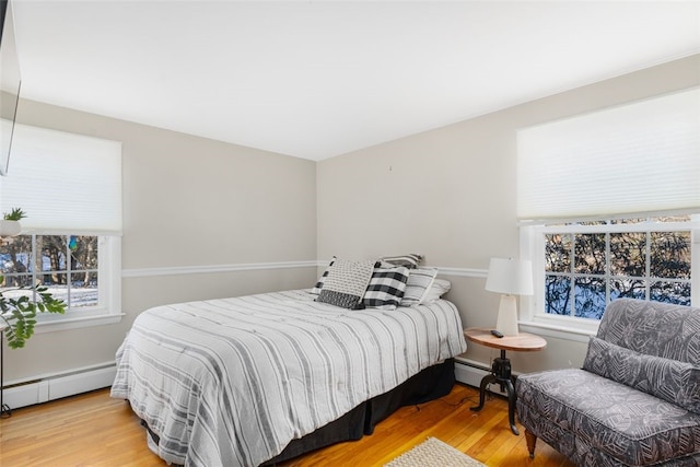 bedroom featuring light hardwood / wood-style floors and a baseboard heating unit