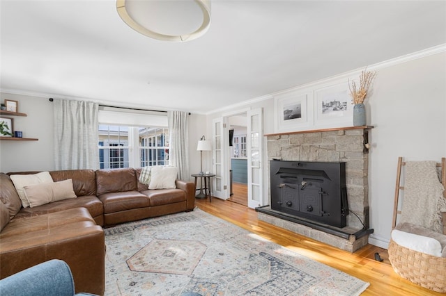 living room featuring hardwood / wood-style floors, a stone fireplace, and crown molding