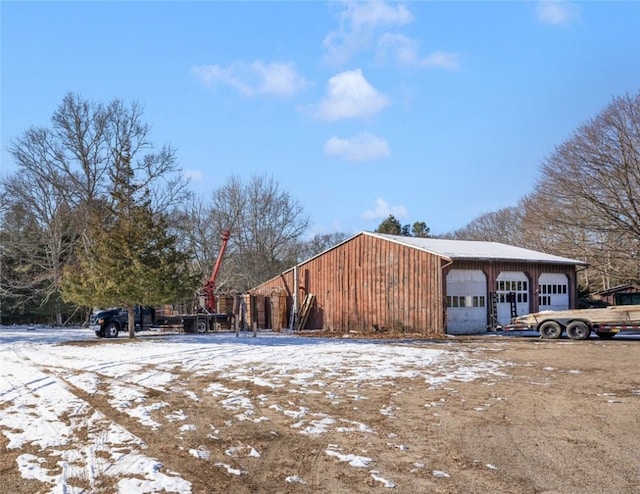 snow covered property with an outbuilding and a garage