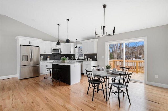 dining space featuring a chandelier, light hardwood / wood-style floors, high vaulted ceiling, and sink