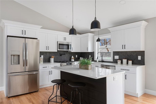 kitchen featuring pendant lighting, a center island, lofted ceiling, white cabinets, and appliances with stainless steel finishes