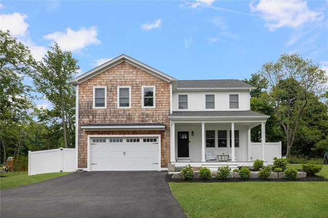 view of front of property featuring a front yard, covered porch, and a garage