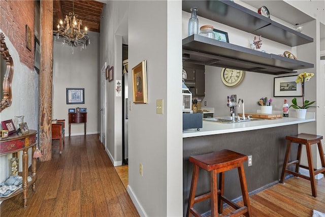 interior space with beam ceiling, sink, wood-type flooring, and a notable chandelier