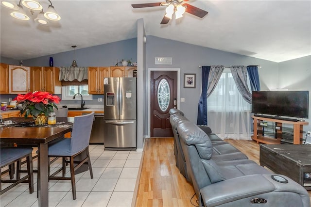 kitchen featuring stainless steel fridge with ice dispenser, sink, decorative light fixtures, ceiling fan, and lofted ceiling