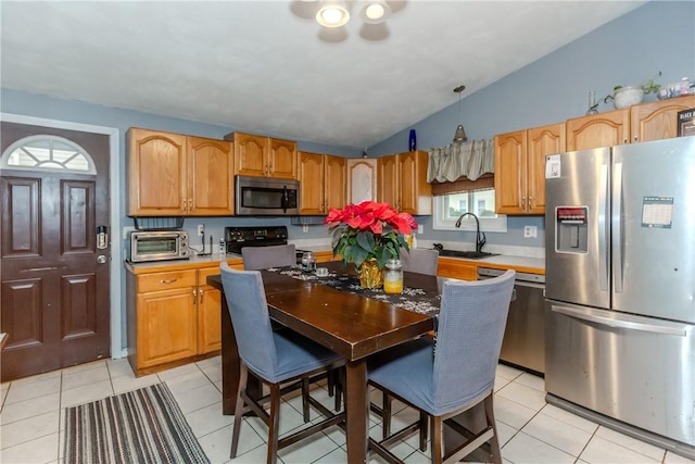 kitchen featuring lofted ceiling, hanging light fixtures, sink, stainless steel appliances, and light tile patterned flooring