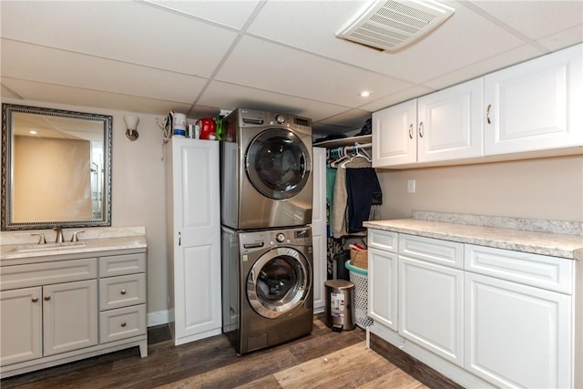 clothes washing area with cabinets, sink, stacked washer / drying machine, and dark hardwood / wood-style floors