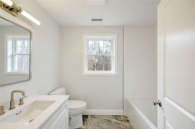 bathroom with a washtub, vanity, and toilet