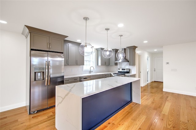 kitchen featuring a center island, hanging light fixtures, wall chimney range hood, backsplash, and appliances with stainless steel finishes