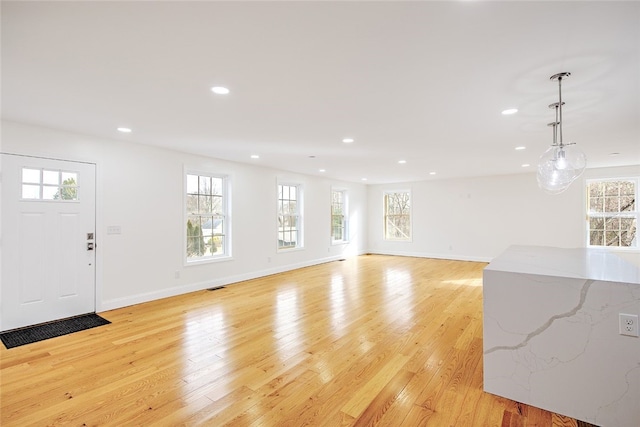 unfurnished living room featuring plenty of natural light and light hardwood / wood-style floors