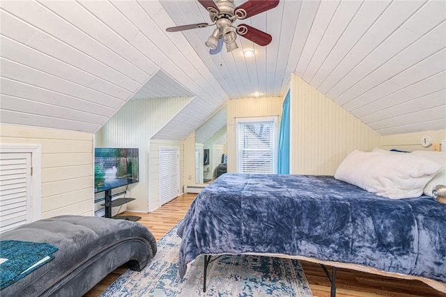 bedroom featuring ceiling fan, baseboard heating, hardwood / wood-style floors, wooden walls, and wood ceiling