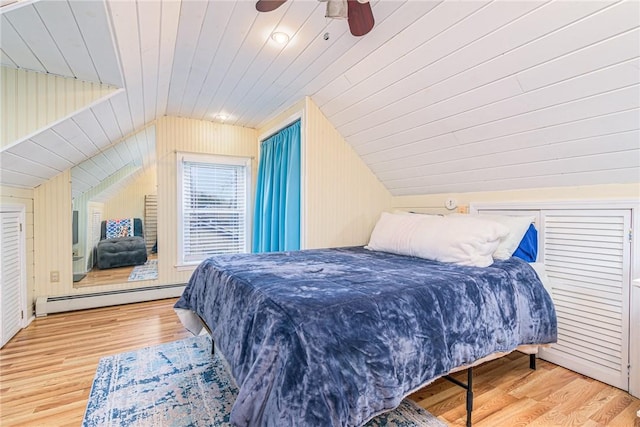 bedroom with baseboard heating, ceiling fan, wood-type flooring, and vaulted ceiling