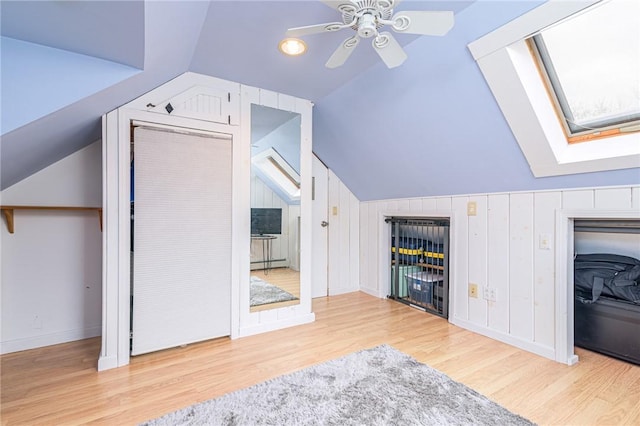 additional living space featuring vaulted ceiling with skylight, ceiling fan, and light hardwood / wood-style floors