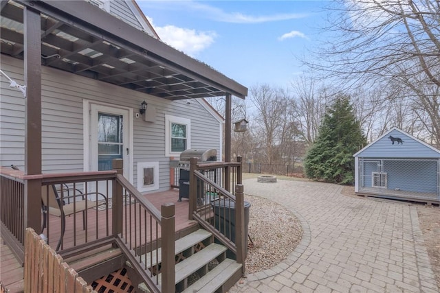 wooden deck with a fire pit, an outbuilding, and grilling area