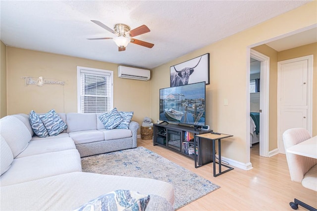 living room with a wall mounted air conditioner, hardwood / wood-style floors, a textured ceiling, and ceiling fan