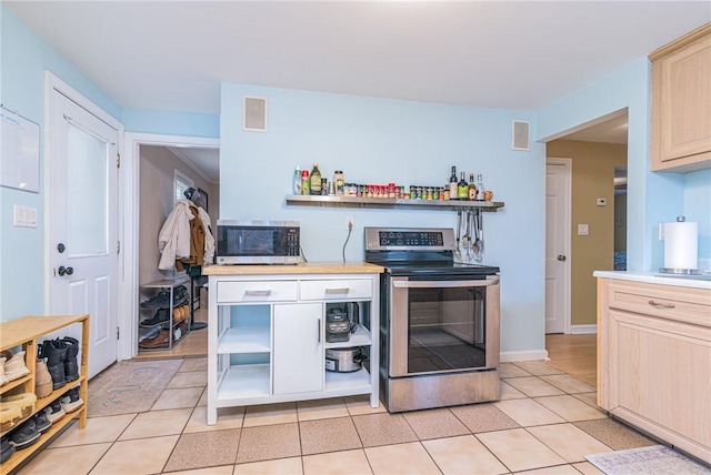 kitchen with light brown cabinets, light tile patterned flooring, and appliances with stainless steel finishes