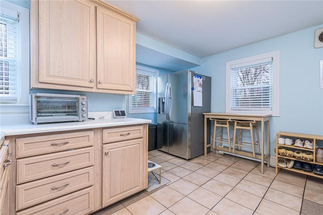 kitchen with stainless steel fridge with ice dispenser, light brown cabinets, and light tile patterned floors