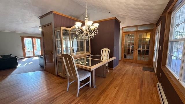 dining area featuring hardwood / wood-style floors, a baseboard radiator, lofted ceiling, ornamental molding, and french doors