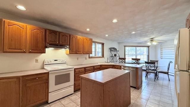 kitchen with light tile patterned flooring, a kitchen island, sink, ceiling fan, and white appliances