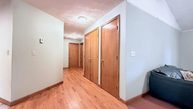 hallway with vaulted ceiling and light hardwood / wood-style floors