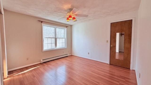 unfurnished room featuring baseboard heating, ceiling fan, and light wood-type flooring