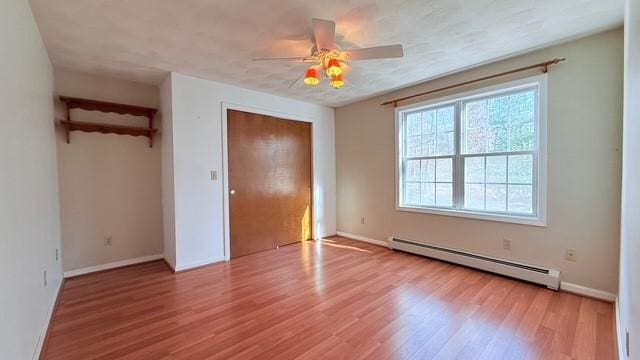 unfurnished bedroom with light wood-type flooring, a closet, ceiling fan, and baseboard heating