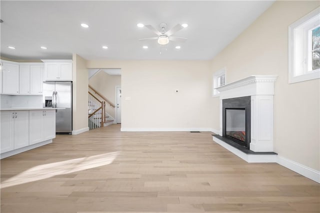 unfurnished living room with ceiling fan and light hardwood / wood-style flooring