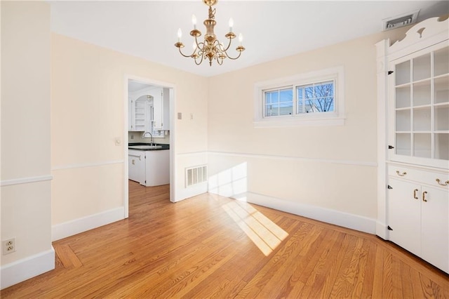 unfurnished dining area featuring light hardwood / wood-style floors, an inviting chandelier, and sink