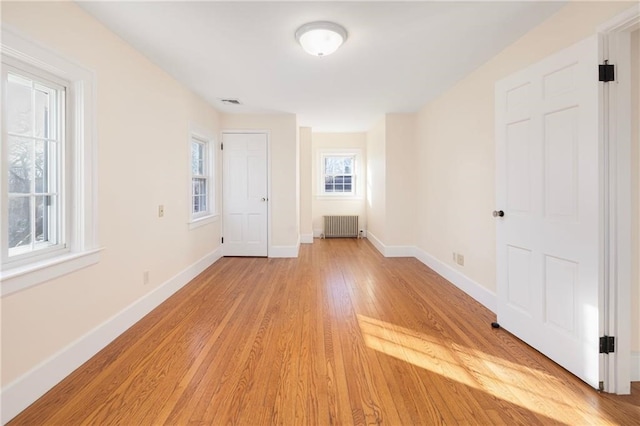 interior space with radiator, light hardwood / wood-style flooring, and plenty of natural light