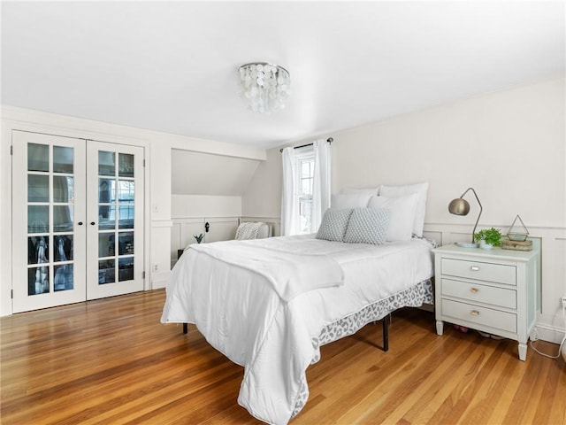 bedroom with light wood-type flooring, lofted ceiling, and access to exterior