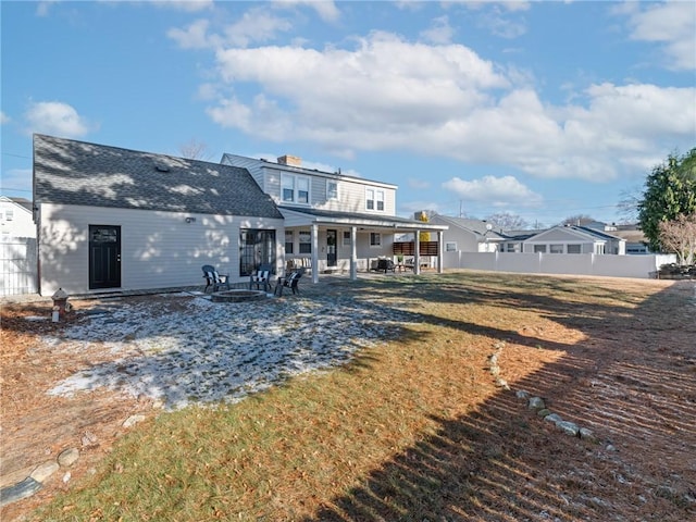 back of property with a fire pit, a patio, and a lawn