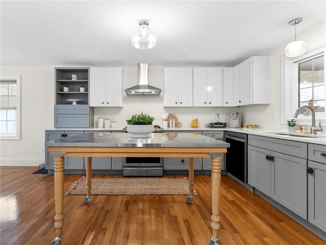 kitchen featuring sink, decorative light fixtures, white cabinets, wall chimney range hood, and gray cabinetry