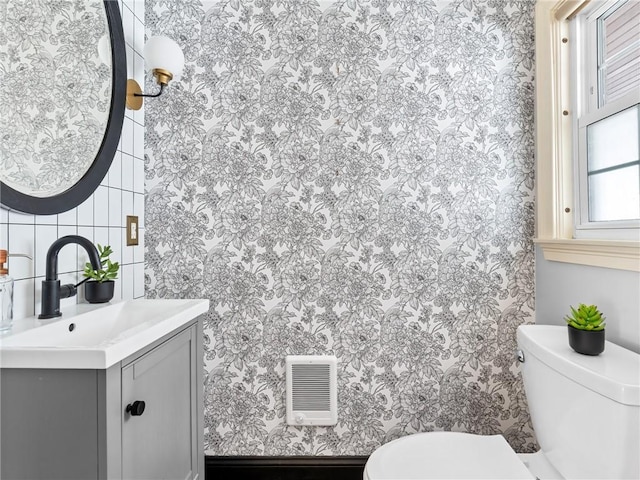 bathroom featuring toilet, vanity, and backsplash