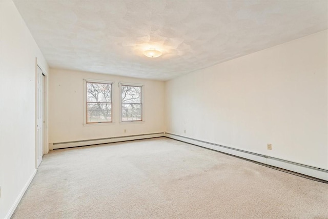 spare room featuring light colored carpet and a baseboard radiator