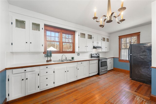 kitchen with stainless steel range with electric cooktop, white cabinetry, black fridge, light hardwood / wood-style flooring, and sink