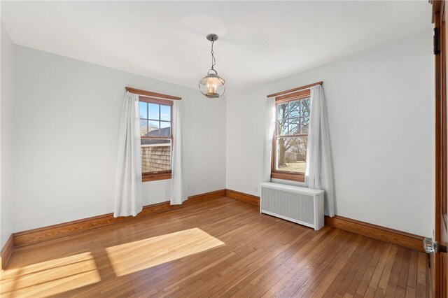 spare room featuring a healthy amount of sunlight, hardwood / wood-style floors, and radiator heating unit