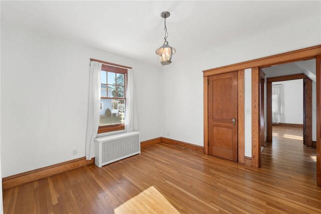 spare room featuring radiator heating unit and hardwood / wood-style floors