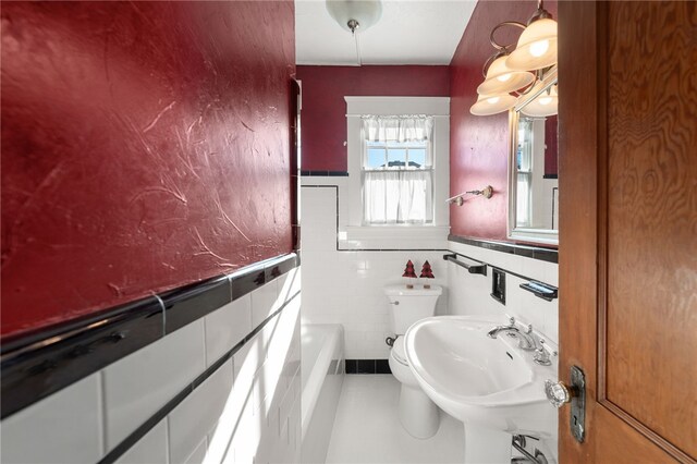 bathroom with tile patterned flooring, tile walls, a bathtub, and sink