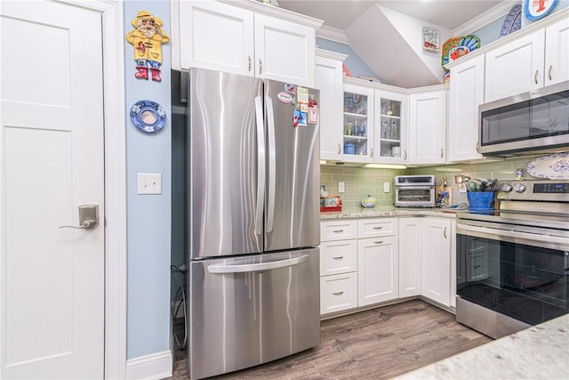 kitchen featuring light stone counters, stainless steel appliances, decorative backsplash, white cabinets, and wood-type flooring