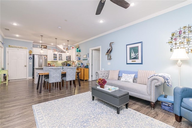 living room featuring dark wood-type flooring, ceiling fan, and crown molding